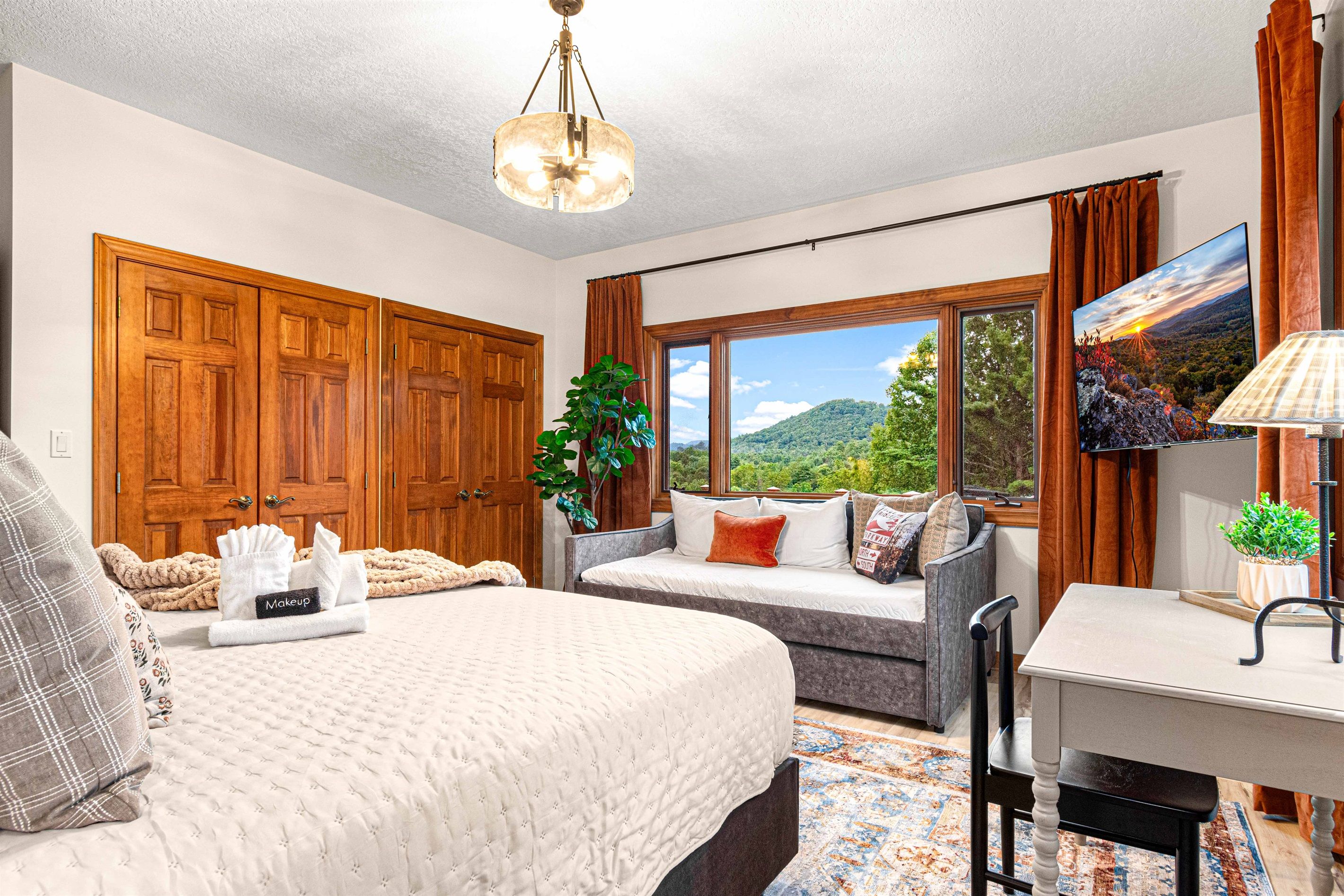 Une chambre à coucher avec un grand lit, un canapé, un bureau et une fenêtre donnant sur l’extérieur.