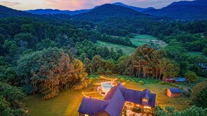 Une grande maison avec une piscine, entourée d’une végétation luxuriante et de collines.