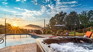 Un espace piscine doté d’un jacuzzi, de chaises longues et de guirlandes lumineuses.