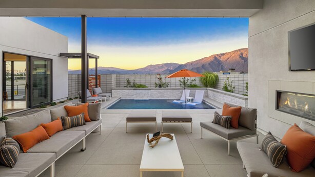 Un espacio exterior moderno con piscina, mobiliario y chimenea.