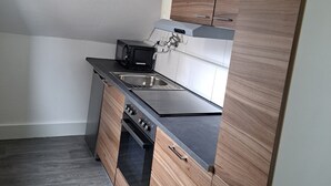 Eine kleine Küche mit integriertem Backofen, Mikrowelle und Spüle.