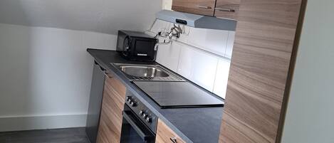 A compact kitchen with a built-in oven, a microwave, and a sink.