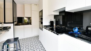 Een moderne keuken met witte kasten, zwarte aanrechtbladen en een vloer met patroon.