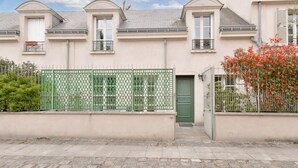 Een rij herenhuisjes met een groen metalen hek, een groene deur en een klein balkon.