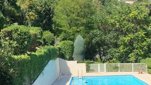 A swimming pool surrounded by lush greenery and a white fence.