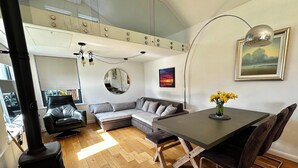 En moderne stue med sofa, spisebord, pejs og et stort spejl.