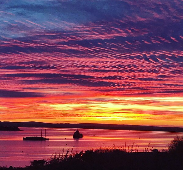 A sunset over a calm body of water with a boat in the foreground.