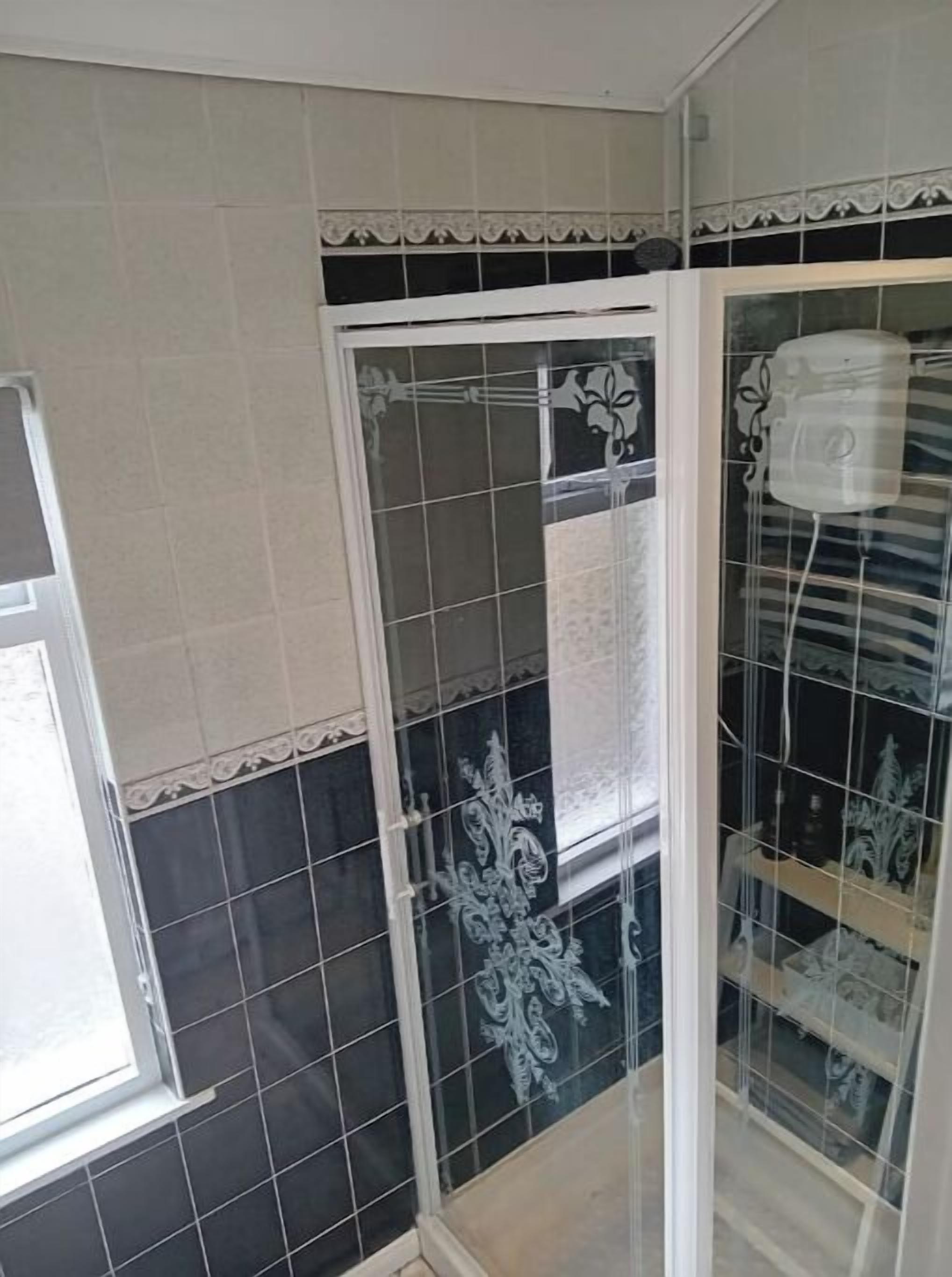 A bathroom with black and white tiles, a white door, and a towel rack.