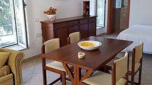 A dining area with a wooden table and chairs, a vase with flowers, and a framed picture on the wall. - LODGE ROSA In the pearl of Cilento, cozy studio apartment, Trentova Bay. (Agropoli)