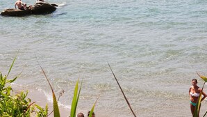 A beach scene with clear water, rocks, and vegetation. - LODGE ROSA In the pearl of Cilento, cozy studio apartment, Trentova Bay. (Agropoli)