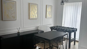 Een moderne keuken met een zwart aanrecht, een eettafel met vier stoelen, en drie ingelijste kunstwerken aan de muur.
