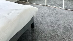 Een slaapkamer met een grote spiegel, een bed, een radiator en een raam.