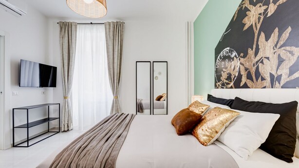 A modern bedroom with a bed, a TV, a mirror, and a large floral artwork on the wall. - BDC - Green Nrg! 2-BDR free parking (Rome)