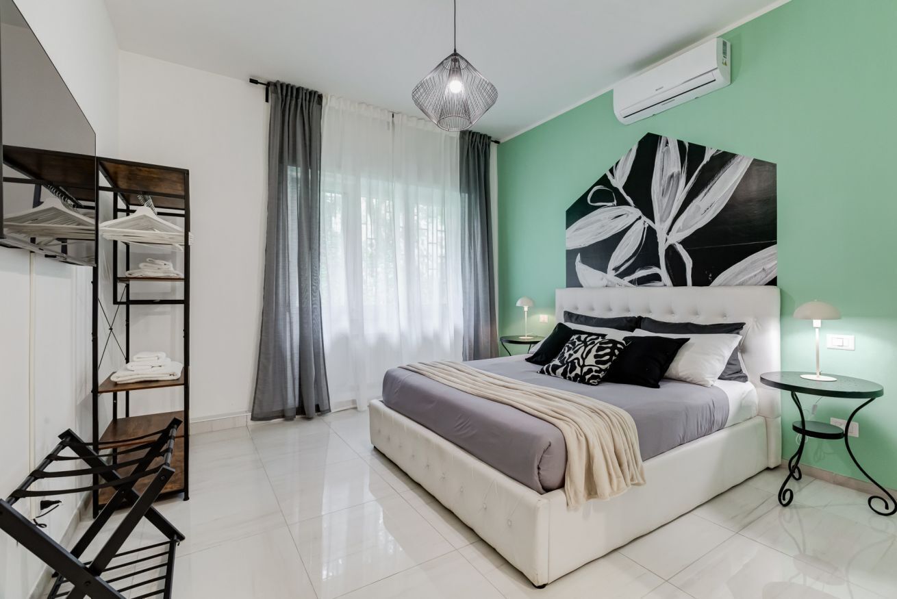 A bedroom with a bed, a wardrobe, a hanging chair, and a pendant light.