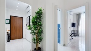 A modern hallway with a potted plant, a wooden door, and a TV mounted on the wall. - BDC - Green Nrg! 2-BDR free parking (Rome)