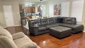 A modern living room with a sectional sofa, a recliner, and hardwood flooring.