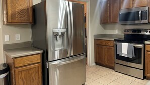 A kitchen with stainless steel appliances, wooden cabinets, and a microwave.