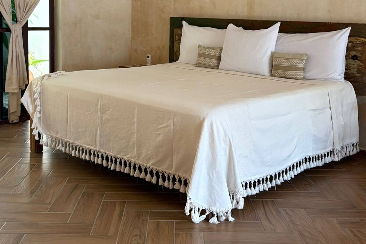 A spacious bedroom with a large bed, a ceiling fan, and a hanging light fixture.