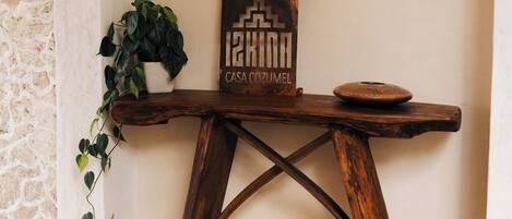 A rustic wooden table with a potted plant and a decorative piece against a white wall with an arched doorway.