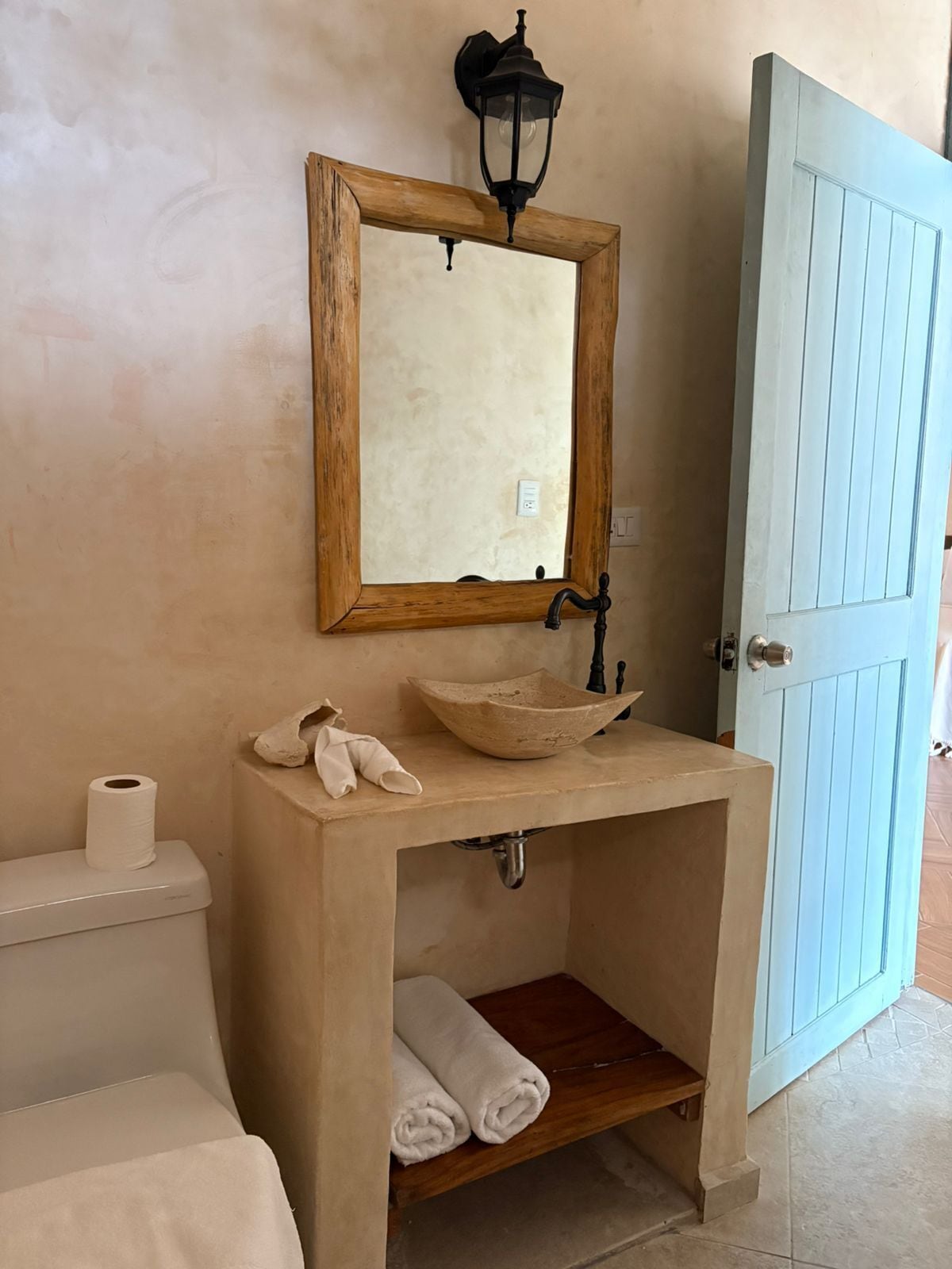 A bathroom with a wooden vanity, a bowl sink, a mirror, a toilet, and a towel rack.