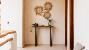 A hallway with a wooden bench, a small table with a vase, and a wall-mounted decorative piece. - Casa Hotel Izkina (Cozumel)