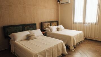 Two beds with wooden headboards, a wooden floor, and a window with curtains.