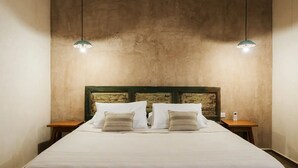 A bed with a wooden headboard, two bedside tables, and two pendant lights. - Casa Hotel Izkina (Cozumel)