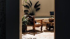 A narrow doorway leading to a room with a tiled floor, a wooden bench, and a potted plant. - Casa Hotel Izkina (Cozumel)