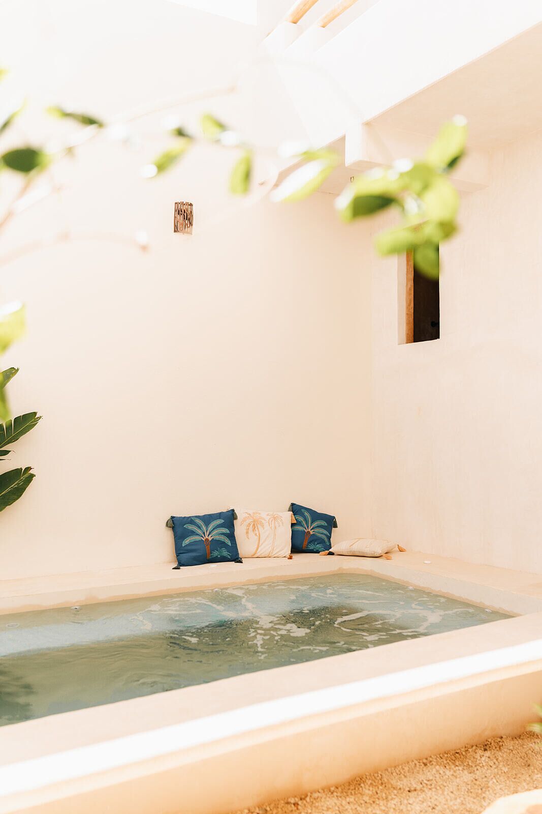 A spa area with a hot tub, two blue pillows, and a small window.