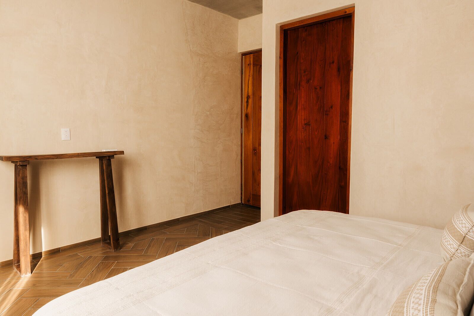 A bedroom with a bed, a wooden table, and a wooden door.