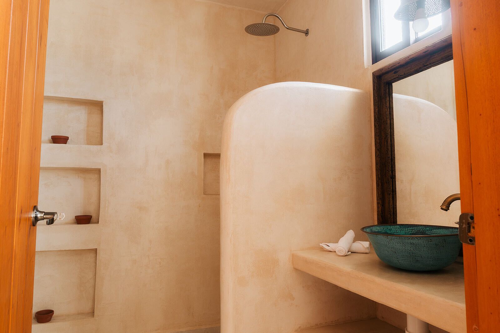 Un baño con ducha, un lavabo y estantes con recipientes pequeños.