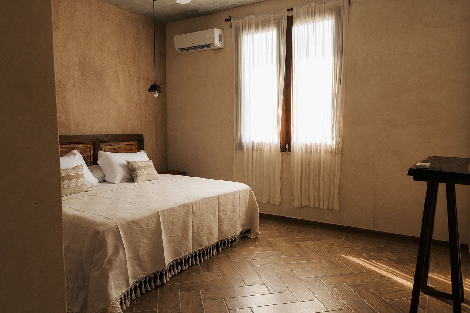 Un dormitorio con cama, mesita de noche, escritorio y aire acondicionado.