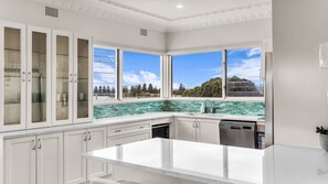 A kitchen with white cabinets, a large island, and a view of trees through the windows.