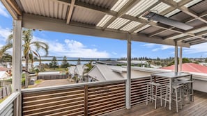 Un espace extérieur abrité avec vue sur la mer, une terrasse en bois et du mobilier d’extérieur.