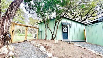 A small, light green shed with a dark door and a small porch.