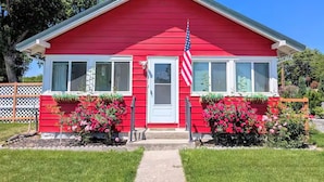A red house with a white door, an American flag, and pink flowers in front. - Downtown Hagerman Hot Springs Getaway (Hagerman)