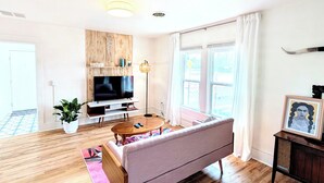 A modern living room with a flat-screen TV, a sofa, a coffee table, and a potted plant. - Downtown Hagerman Hot Springs Getaway (Hagerman)