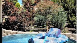 A hot tub with a leaf-patterned inflatable seat, surrounded by trees and a stone wall. - Downtown Hagerman Hot Springs Getaway (Hagerman)