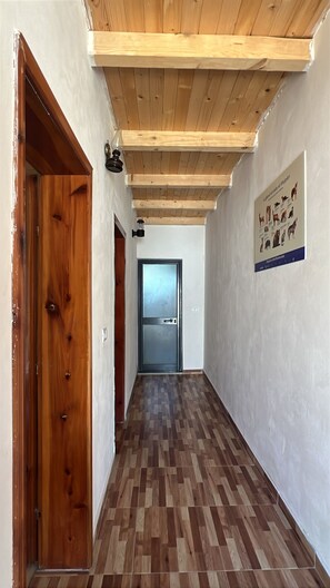 A hallway with wooden flooring, a wooden ceiling, and a door on the left. - Lule bore (Lekbibaj)