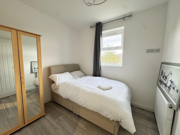 A bedroom with a bed, a wardrobe, a window, and a radiator.