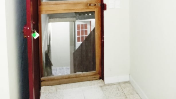 Una habitación con puerta de madera, una ventana pequeña y un cuadro enmarcado en la pared.
