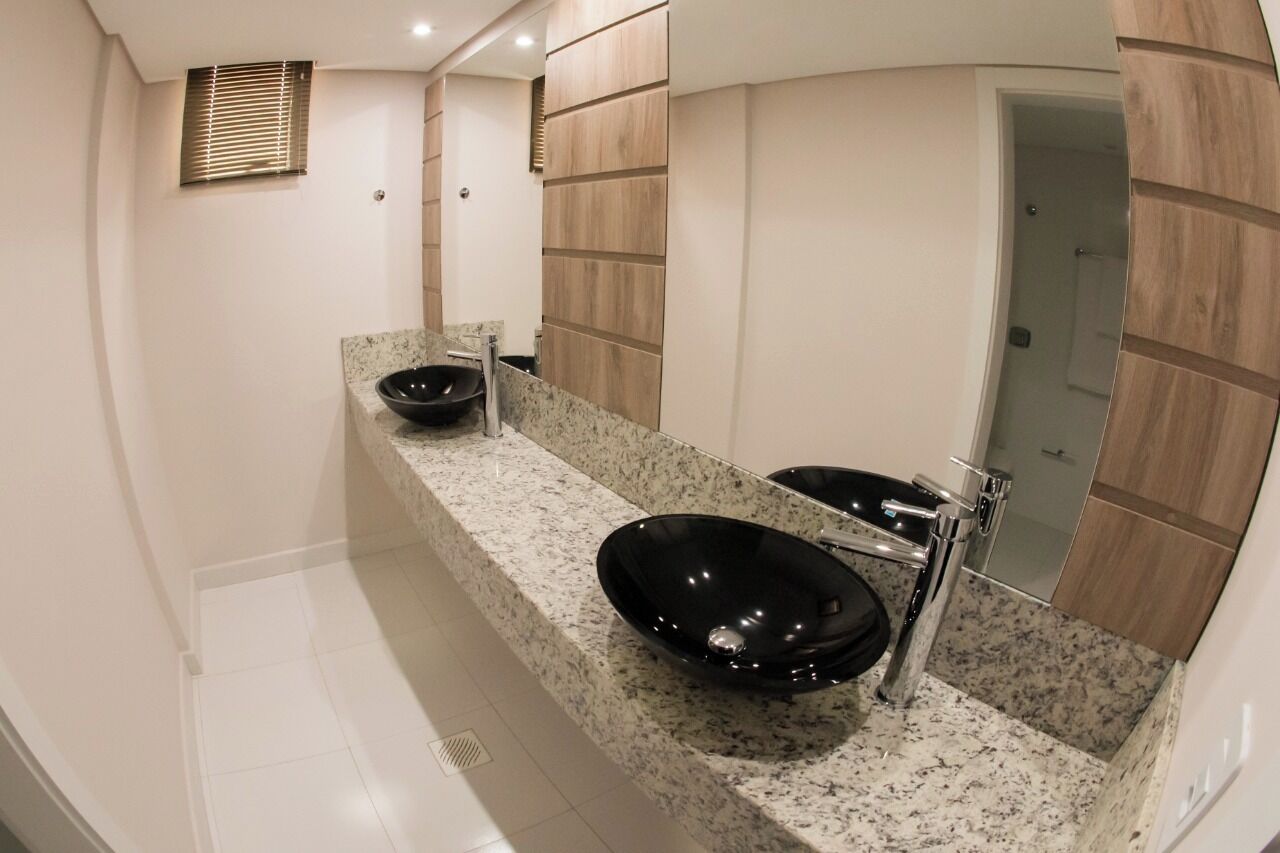 A modern bathroom with two black vessel sinks, a large mirror, and wooden paneling on the walls.