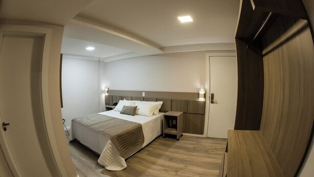 A bedroom with a bed, bedside tables, and a wardrobe. - LARANJEIRAS PALACE HOTEL (Laranjeiras do Sul)