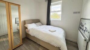Un dormitorio con cama, armario, ventana y radiador.
