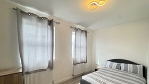 Un dormitorio con cama, cortinas y radiador.