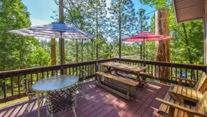 A wooden deck with a table and benches, surrounded by trees. - The cozy cabin! (Twain Harte)