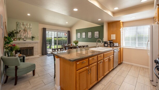 A spacious kitchen with a large island, wooden cabinets, and a dining area with a view of the outdoors. - Huge Backyard, Near Disney, Family Friendly, Quiet Neighborhood (Placentia)