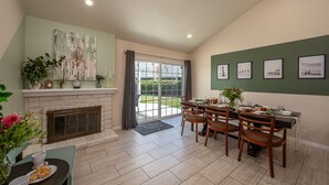 A dining area with a fireplace, a dining table set for four, and a view through the glass door to the outdoors. - Huge Backyard, Near Disney, Family Friendly, Quiet Neighborhood (Placentia)