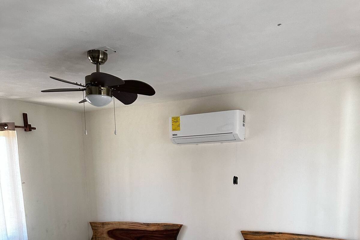 A room with two beds, a ceiling fan, and an air conditioning unit.