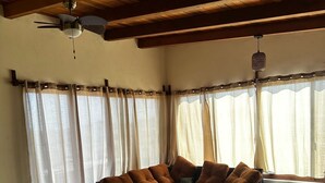 A cozy living room with a sectional sofa, a round coffee table, and a bed with a green quilt. - Puesta de sol (Ixtapa)